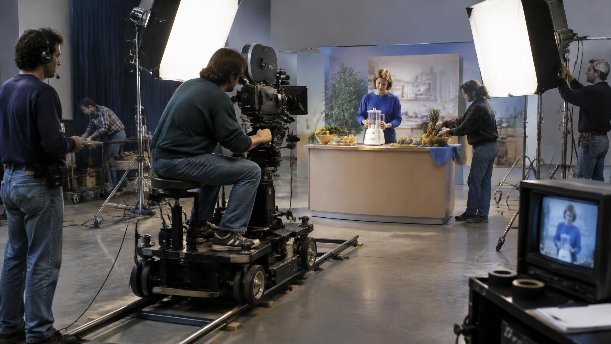 Film crew filming a television commercial on a studio set with lighting rigs