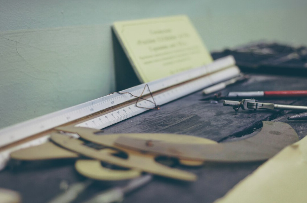Graphic designer's drafting table covered with old advertising layouts and typesetting tools